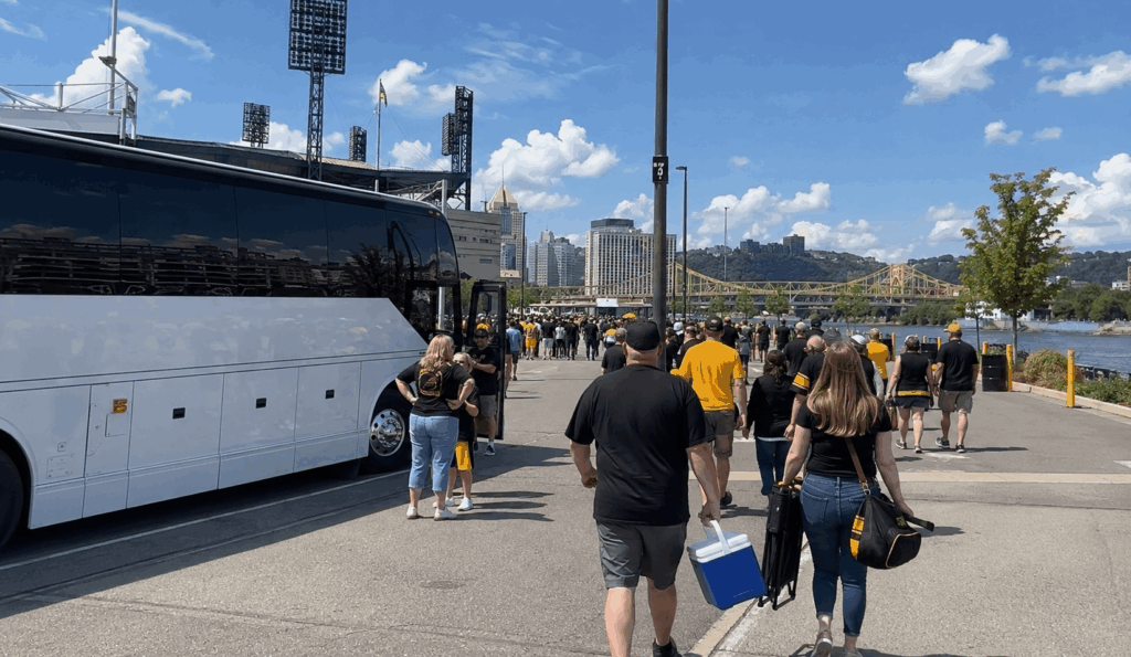 group of sports fans gathering near a charter bus before a game on pittsburgh's north shore