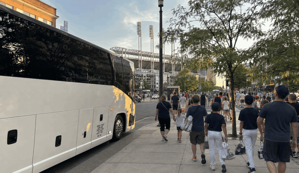 group travelers walking from a charter bus toward progressive field before first pitch