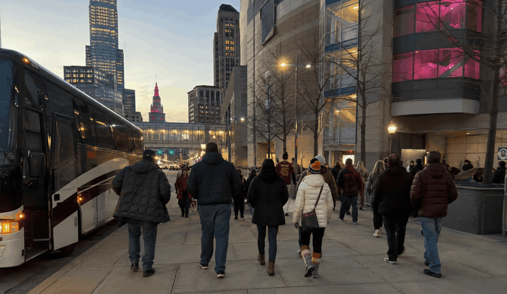 group of basketball fans walking from a charter bus toward rocket mortgage fieldhouse before tip-off